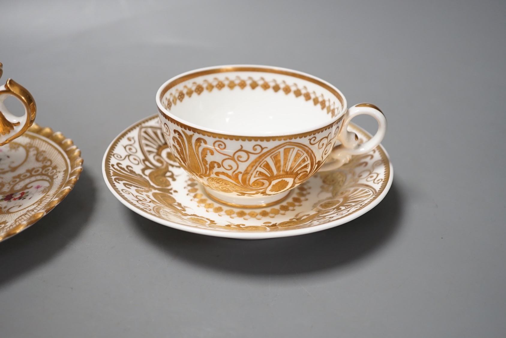 A Chamberlains Worcester gadroon bordered coffee cup and saucer painted with flowers, printed mark in puce and a Spode teacup and saucer with raised gilding in neo-classical style pattern 4327, mark and pattern in red